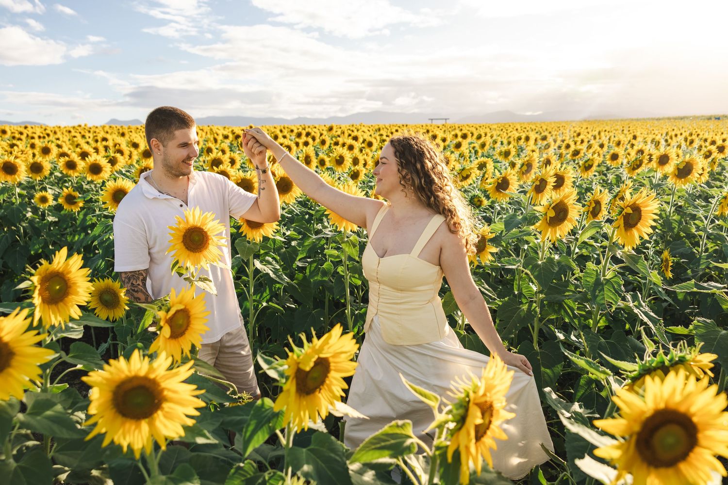 People enjoying a beautiful summer day in a vibrant yellow sunflower field under blue skies.