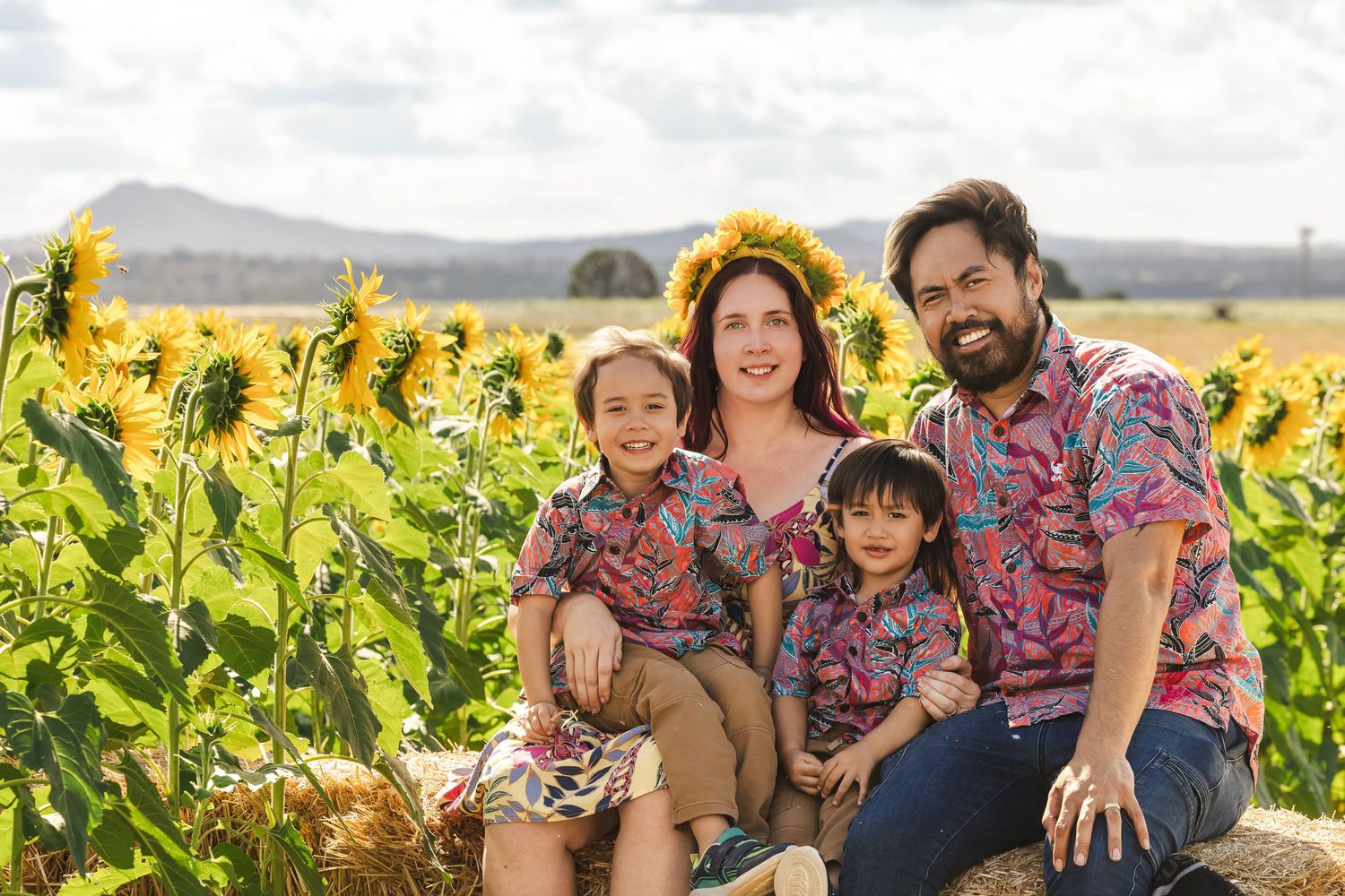 Family enjoying a sunny day together in a vibrant yellow sunflower field during golden hour.