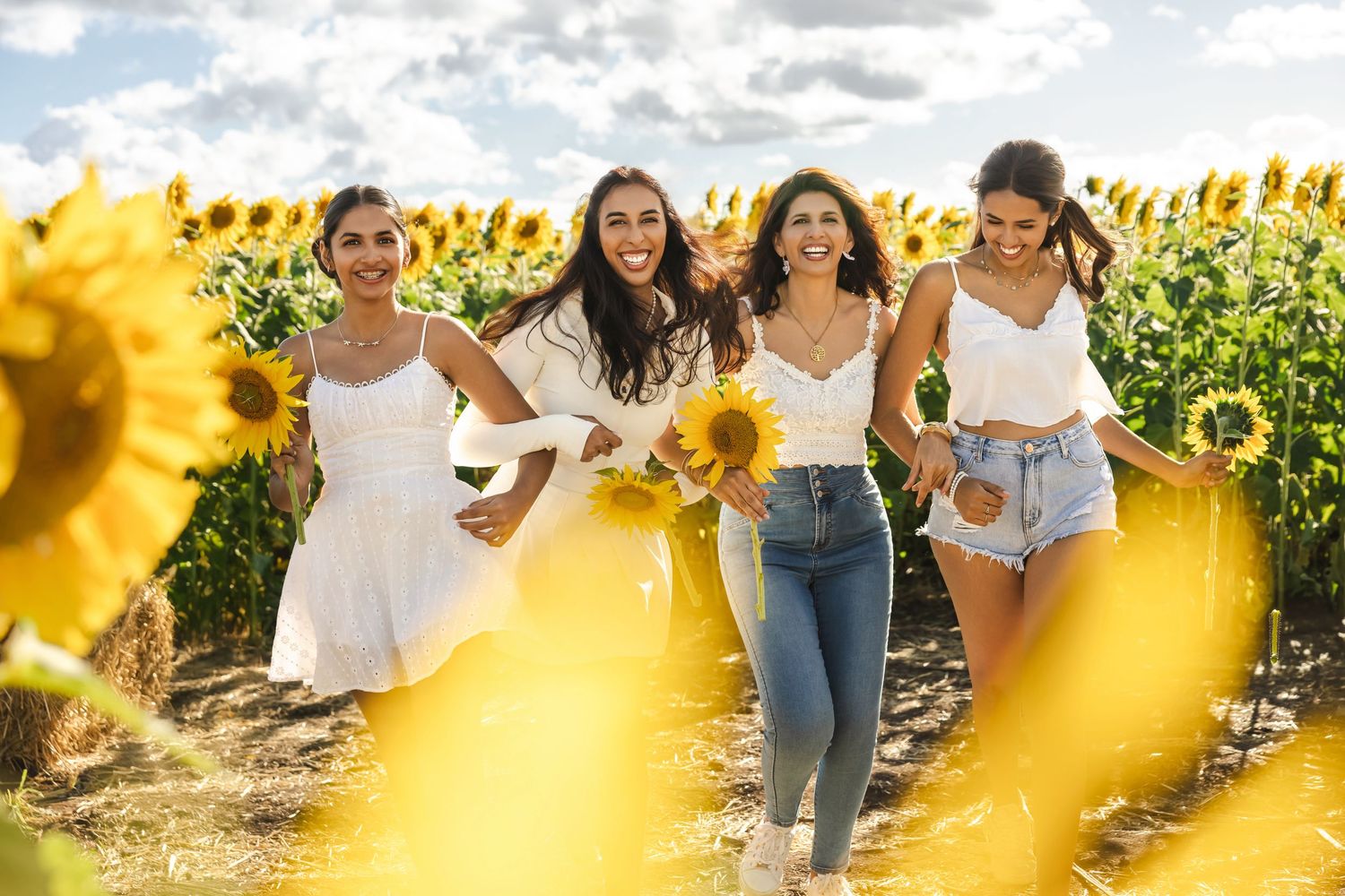 A group of friends walk together through a vibrant sunflower field on a sunny summer day.