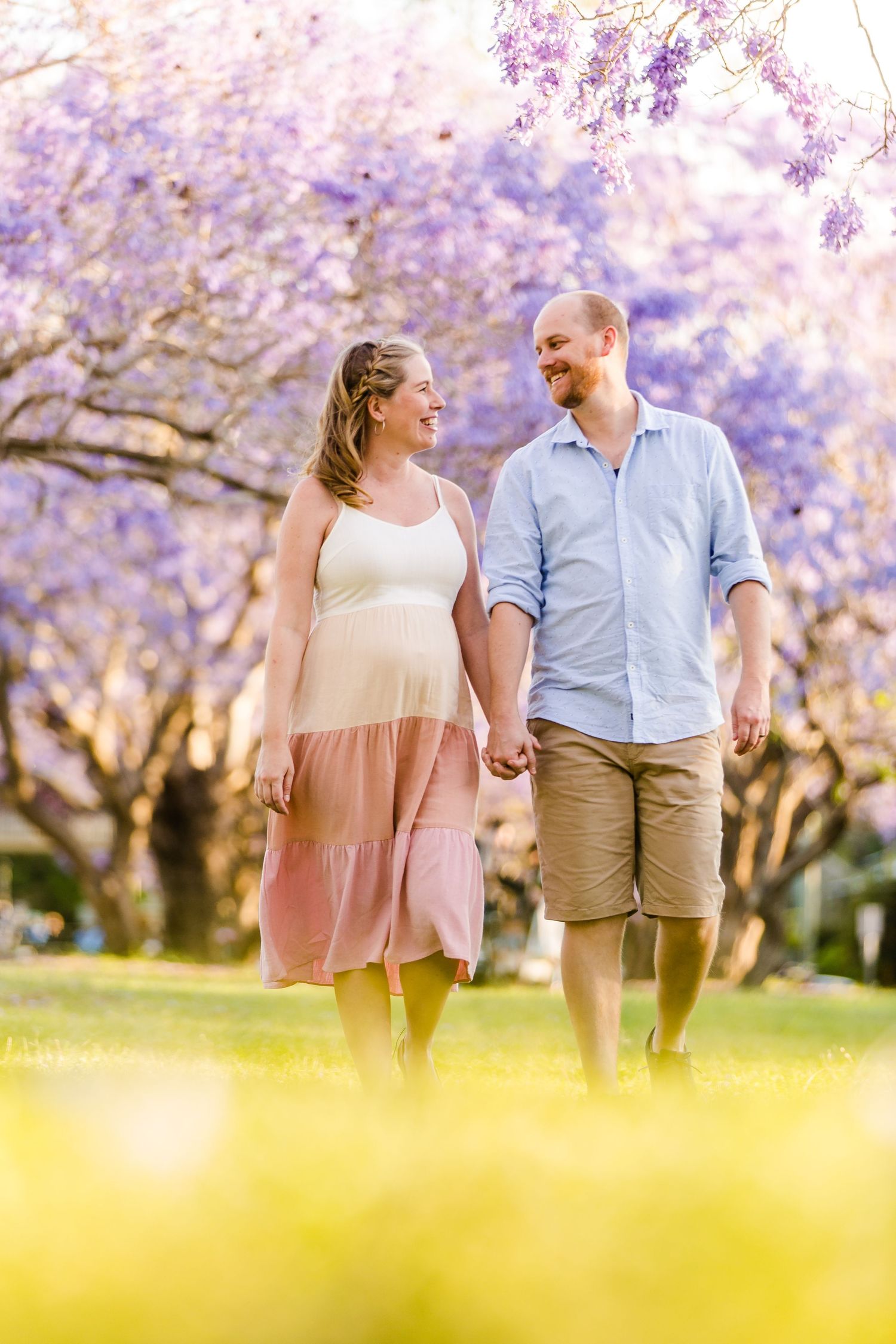 A couple walks together beneath blooming cherry blossom trees in a spring garden setting.