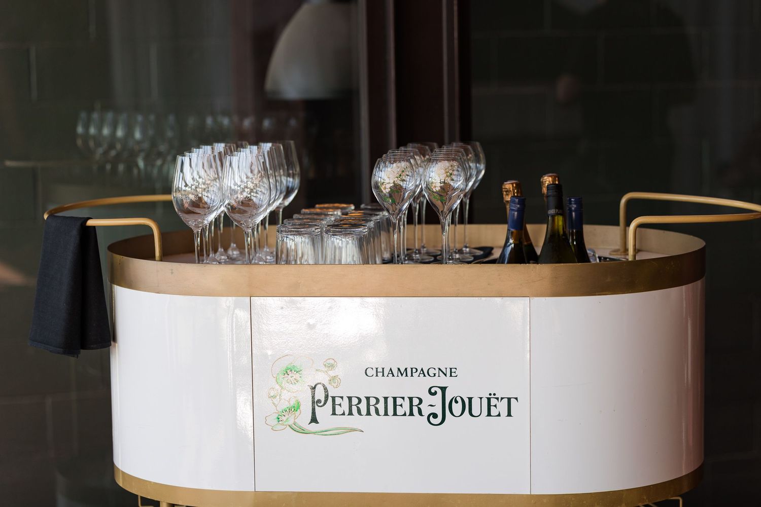 Perrier-Jouët Champagne bar display with elegant crystal glasses and bottles on a white and gold rounded counter.