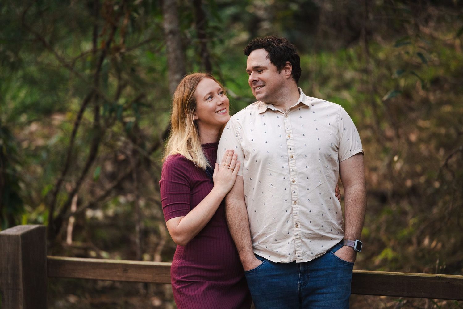 A couple shares tender moments together while walking through a scenic wooded area in autumn.