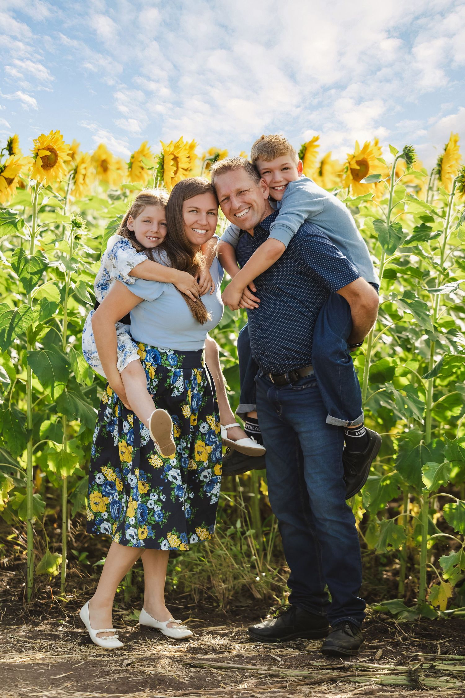 Happy family with two kids enjoying a sunny day in a vibrant sunflower field.