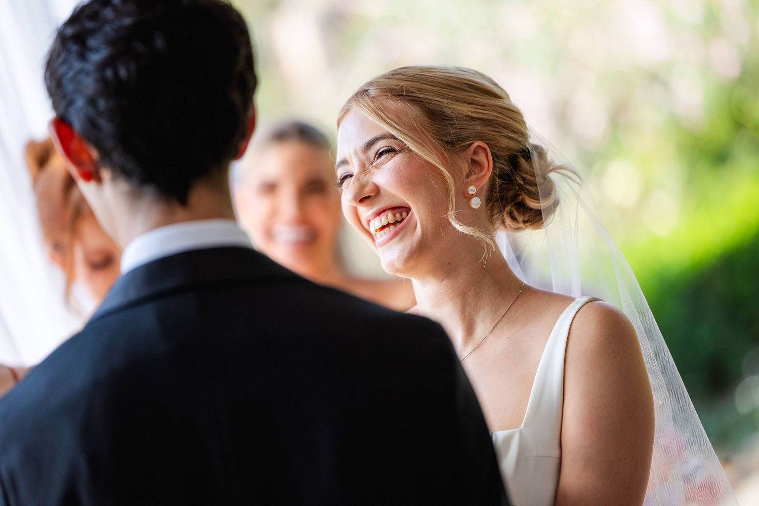 Joyful wedding celebration scene with people laughing and smiling outdoors in natural lighting.