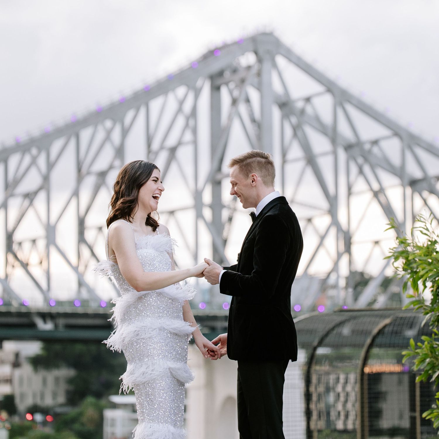Newlywed couple dancing and celebrating their wedding day with Montreal's iconic Jacques Cartier Bridge in the background.