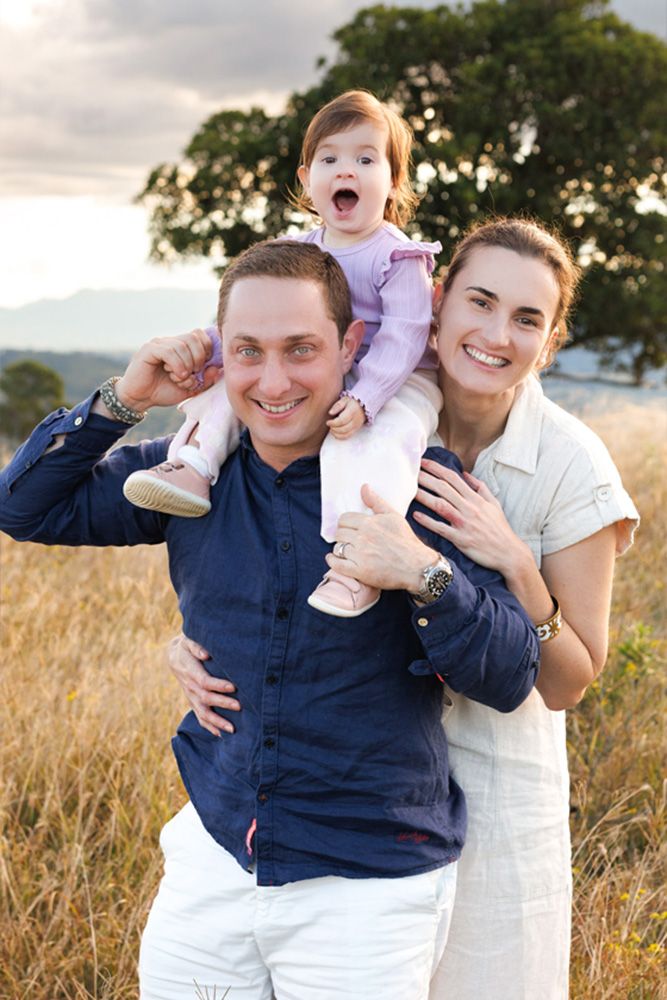 Family photo in golden field showing joyful expressions during sunset.