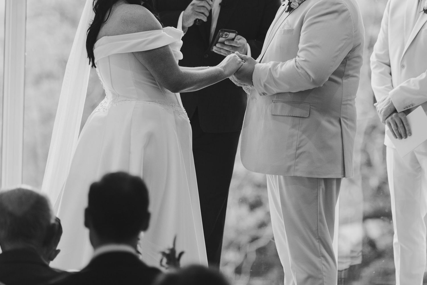 Black and white wedding ceremony photo of bride and groom exchanging rings at the altar.