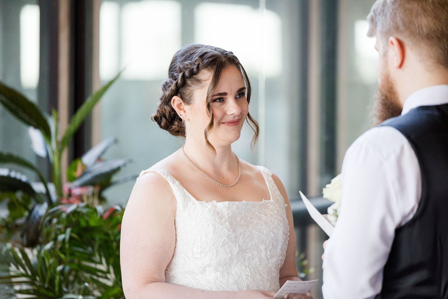 Bride smiling warmly at groom during intimate wedding ceremony vows in a sunlit venue.