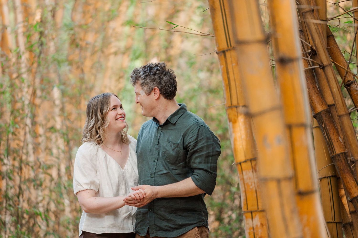 A couple shares a romantic moment in a bamboo forest with warm golden sunlight filtering through the trees.