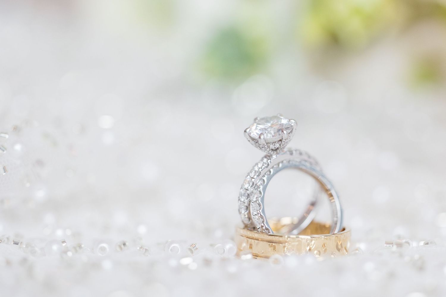 A sparkling diamond engagement ring and gold wedding band nestled among delicate crystal decorations.