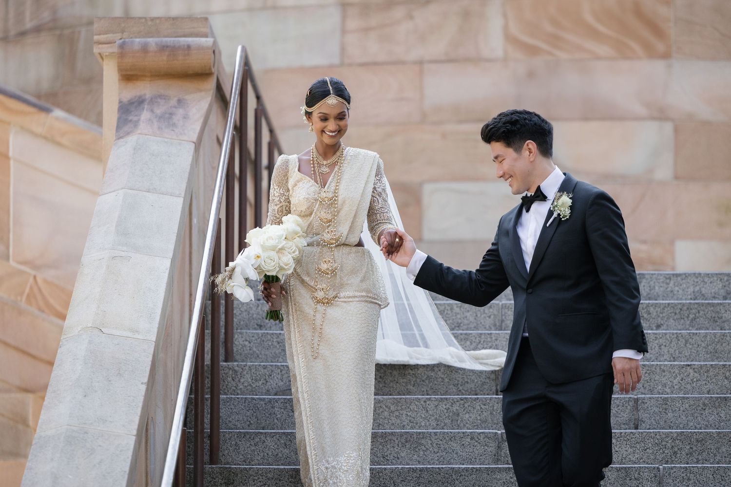 A bride and groom share a romantic moment on stone steps during their wedding photoshoot.