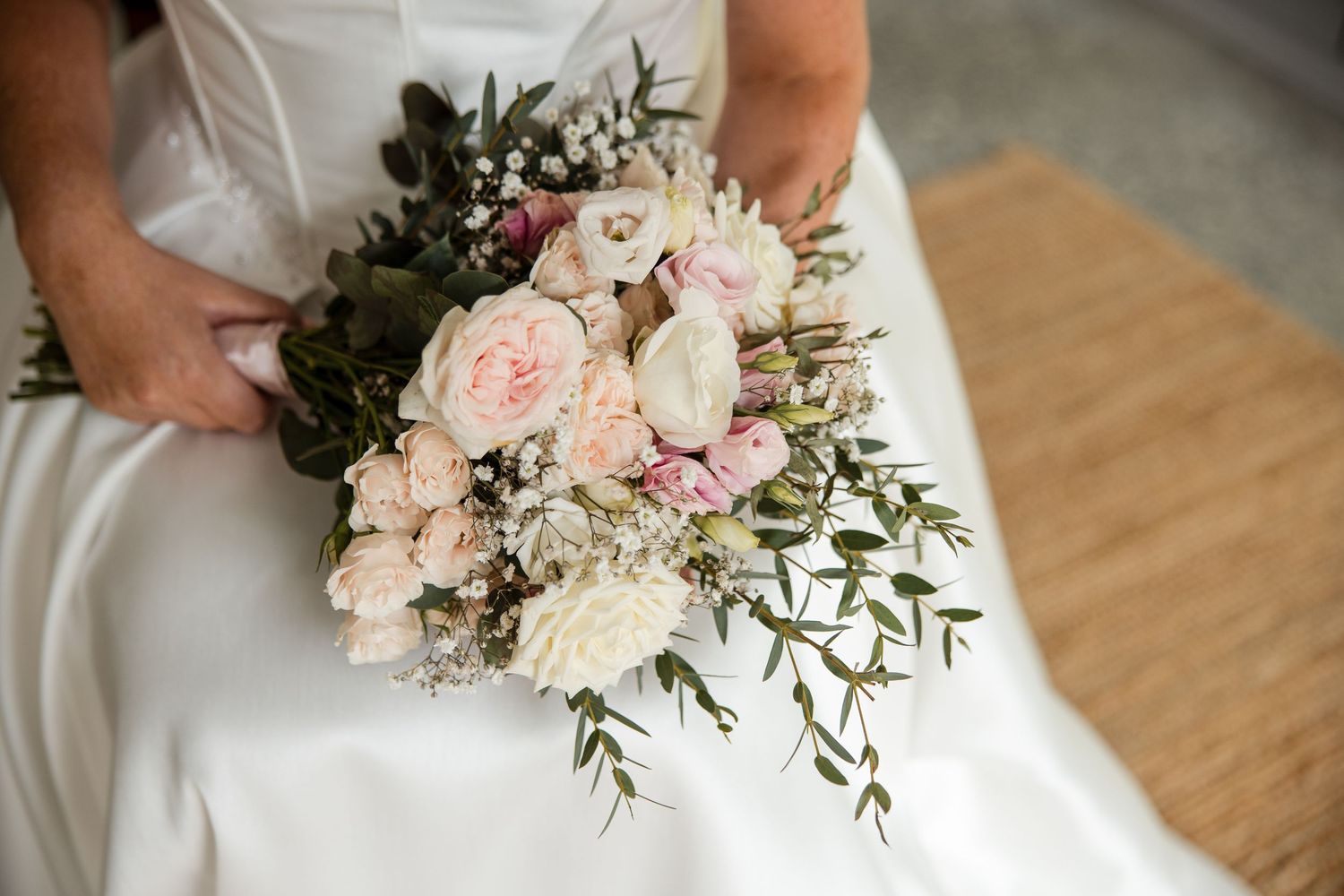 Bride holding a romantic blush pink and white wedding bouquet with eucalyptus greenery and peonies.