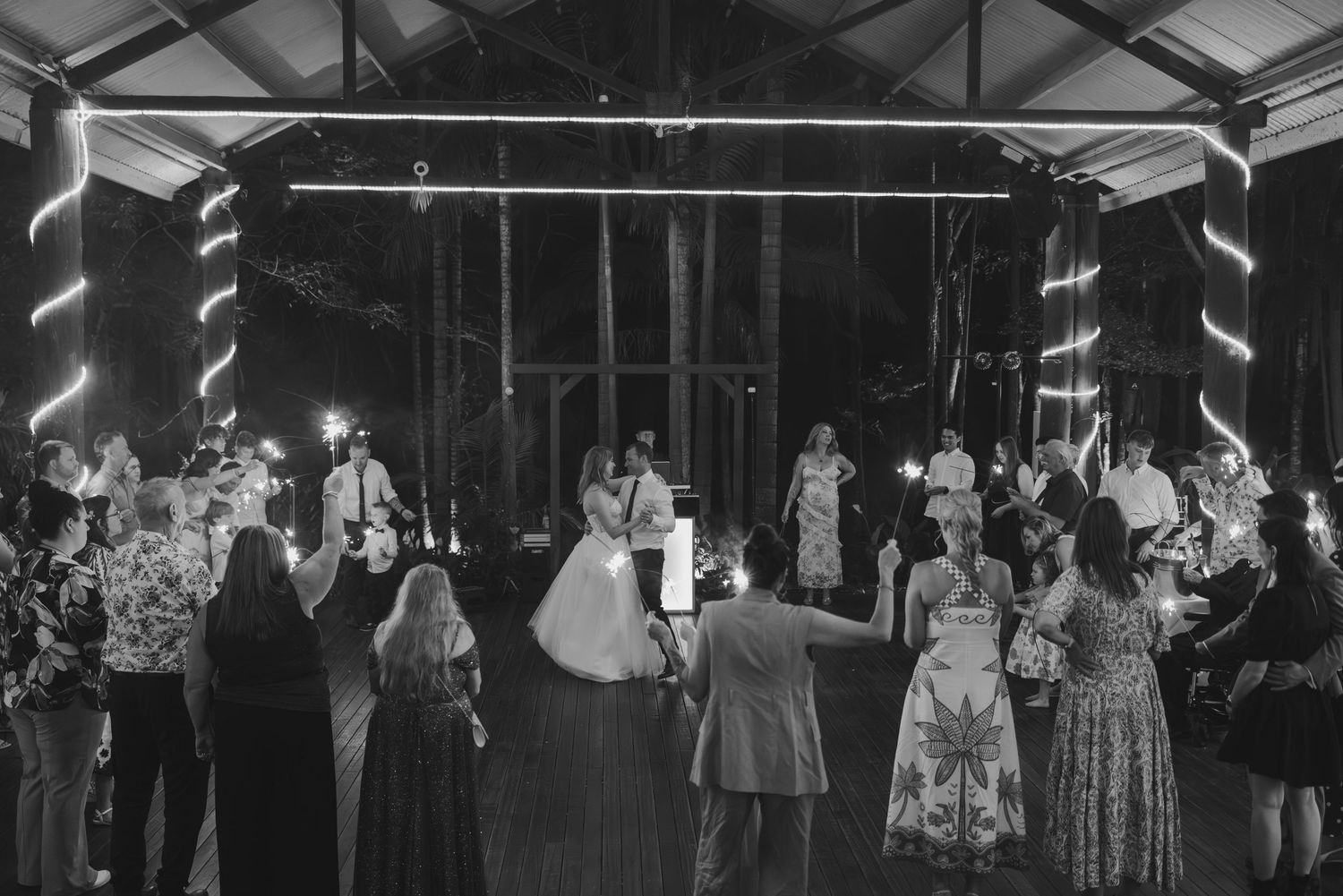 Vintage black and white photograph of couples dancing at a social gathering in an indoor venue with decorative lighting.