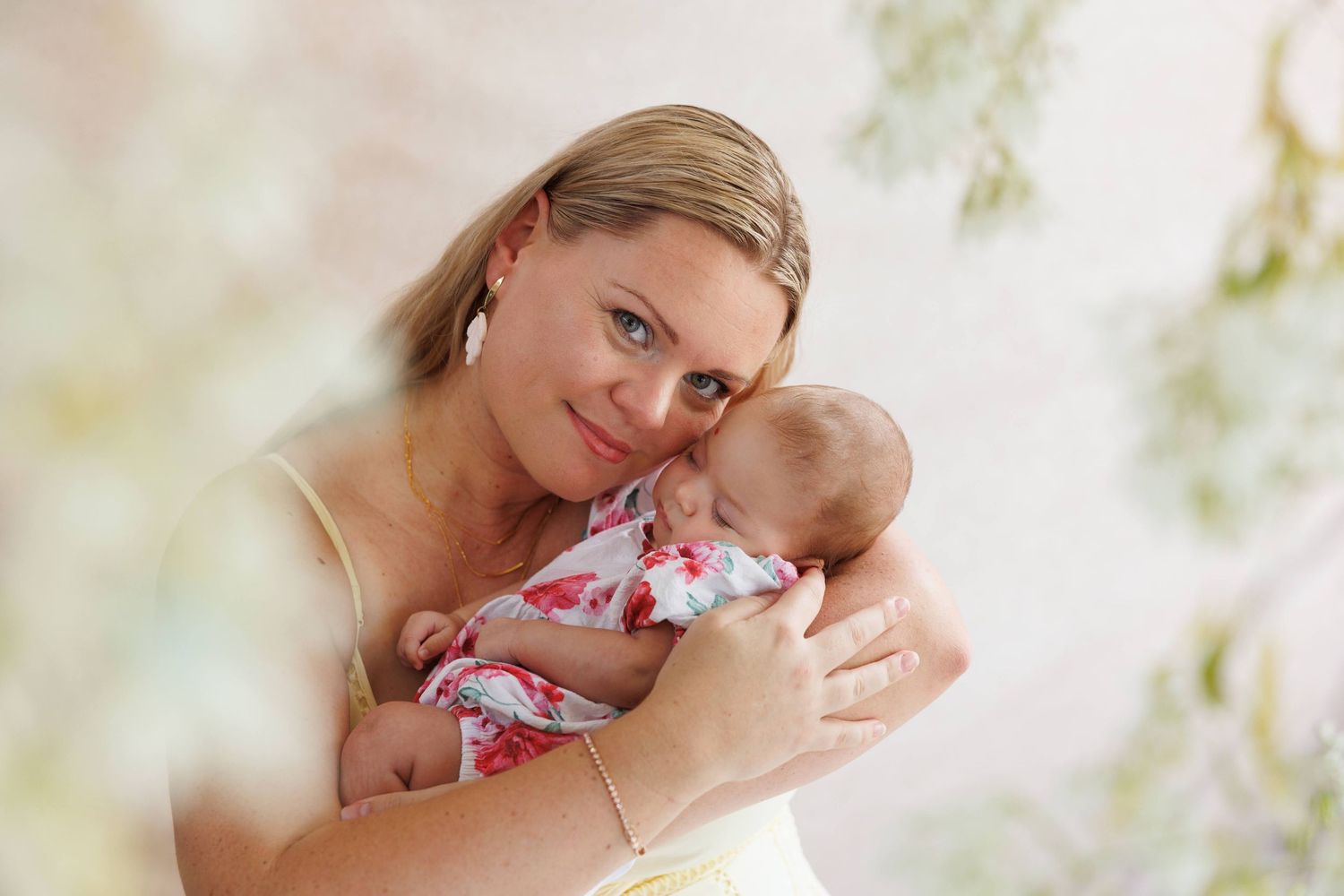 A tender moment between parent and infant in soft natural light, with the baby wearing a floral patterned outfit.