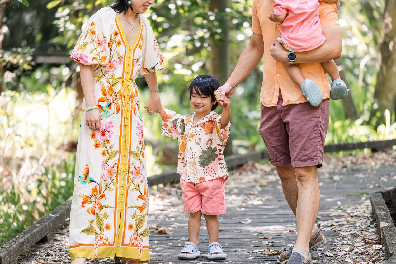 A group of people walking on a wooded path in coordinated pink and orange summer outfits.