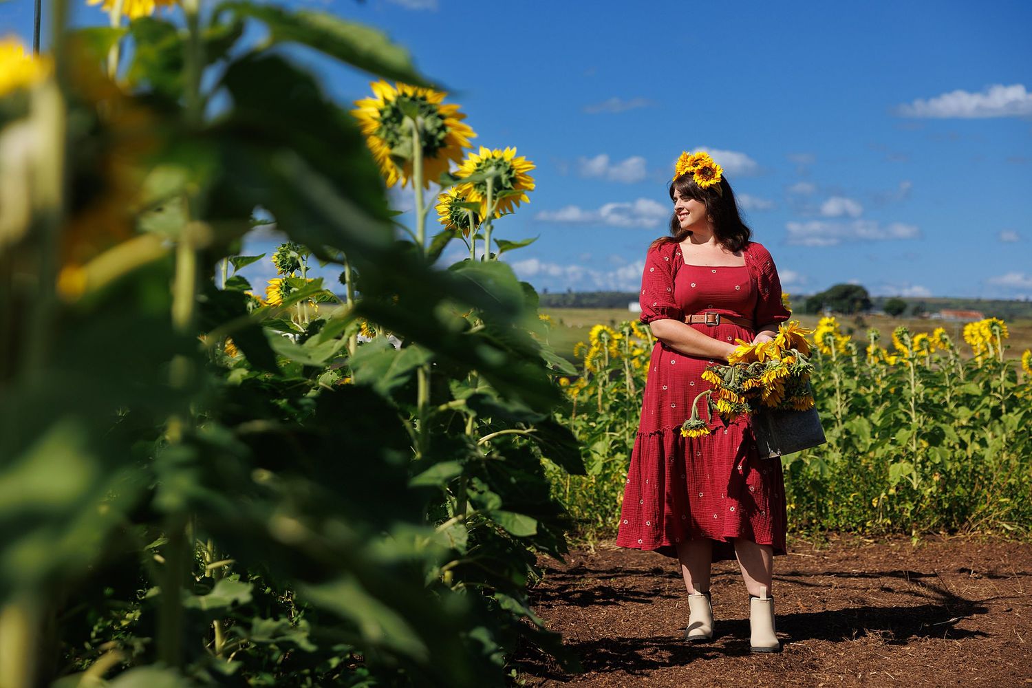 Red maxi dress figure in a beautiful sunflower field on a sunny afternoon with blue skies.