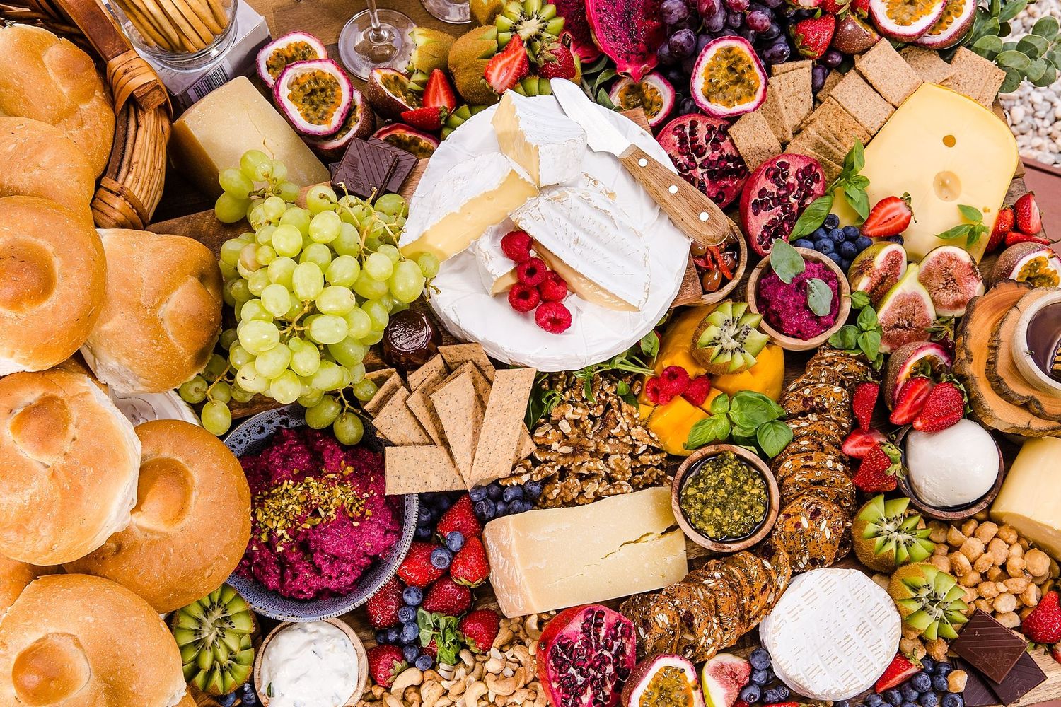 Overhead view of a colorful charcuterie board with meats, cheeses, fruits, nuts, and bread arranged artfully.