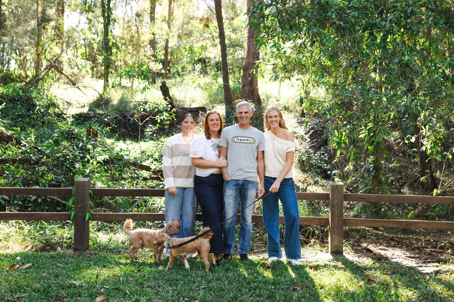A series of outdoor family photos taken in a lush green garden setting with wooden fencing and natural lighting.