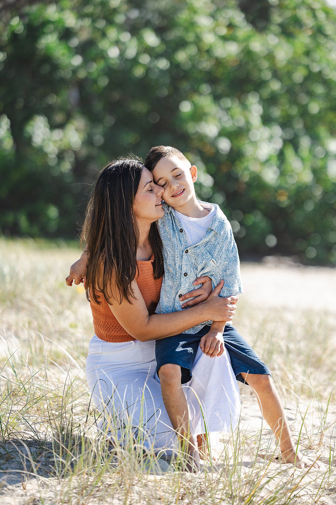 A tender moment shared between in an outdoor setting with golden grass and soft bokeh lighting in the background.