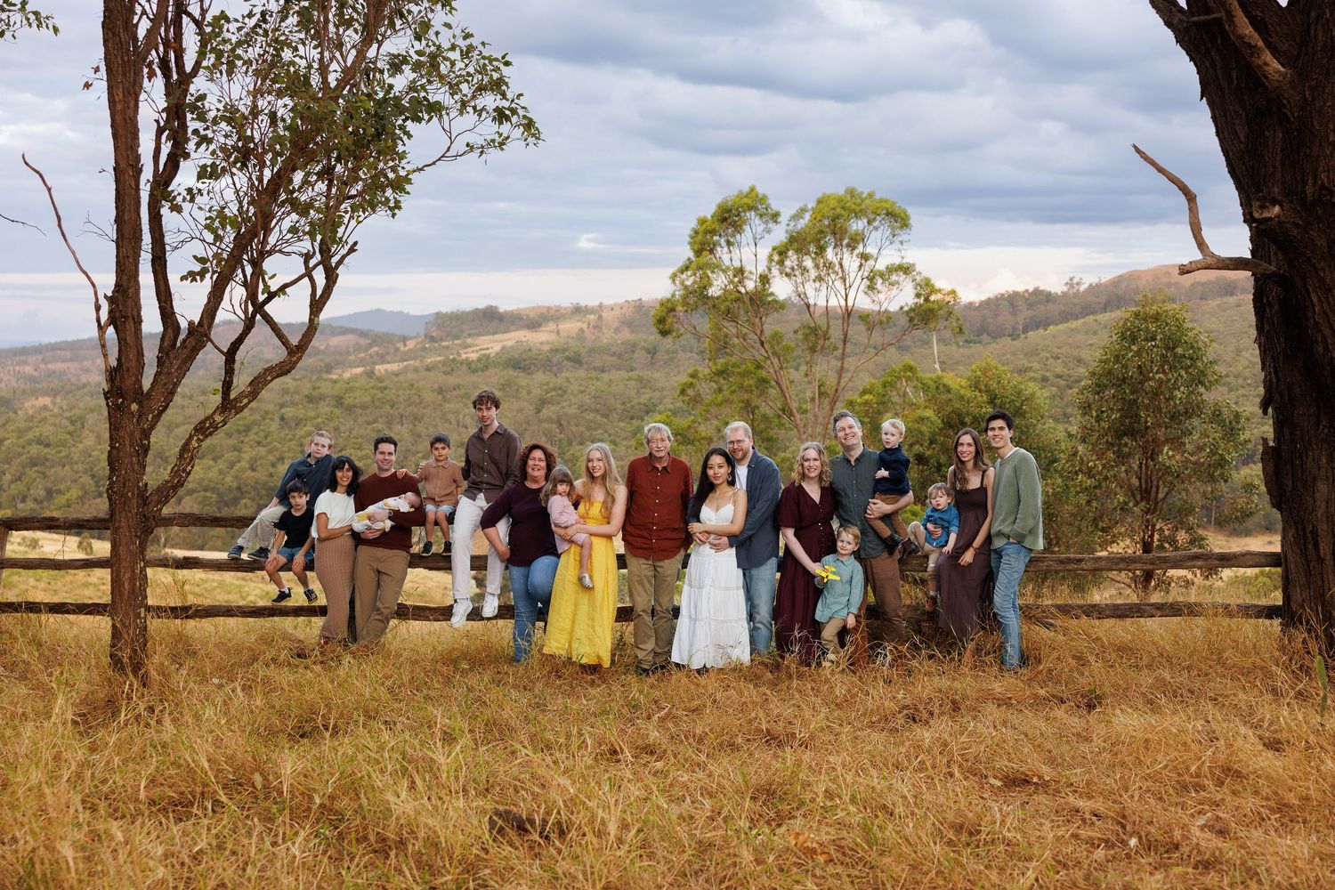 A group gathers in the Australian bush landscape with gum trees and rolling hills in the background.