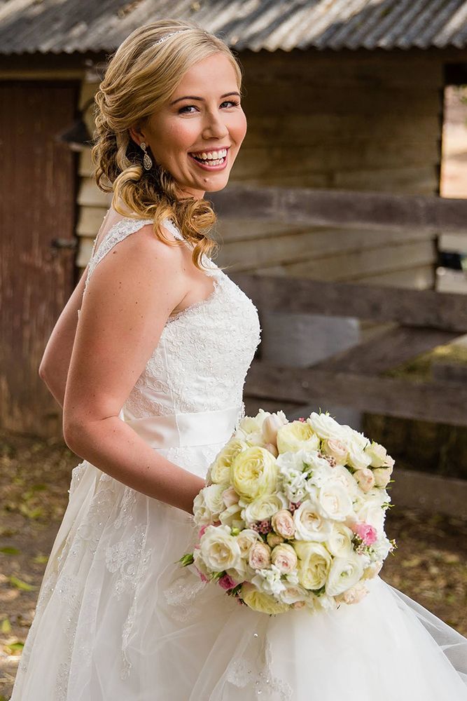 A bridal portrait featuring an elegant white bouquet of roses and lilies.