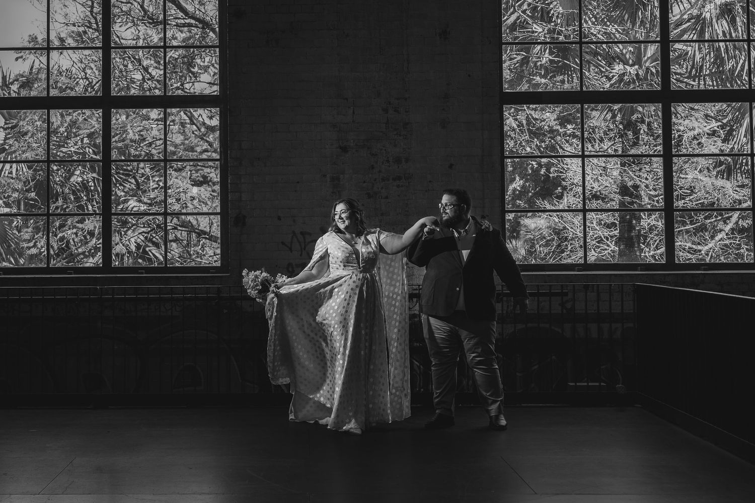 A sequence of black and white dance movements captured through large windows in a studio space.