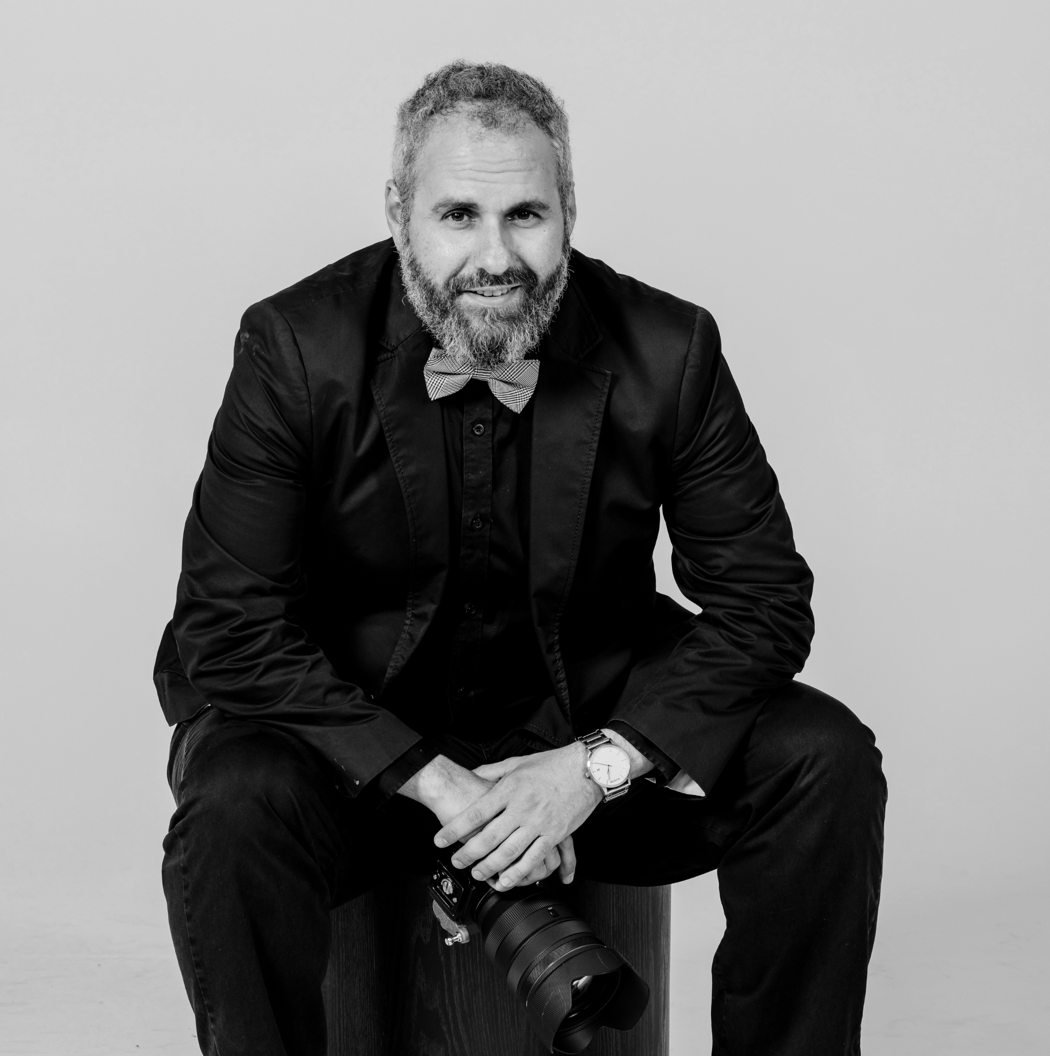 A black and white photo series showing someone in a dark suit seated in various contemplative poses.
