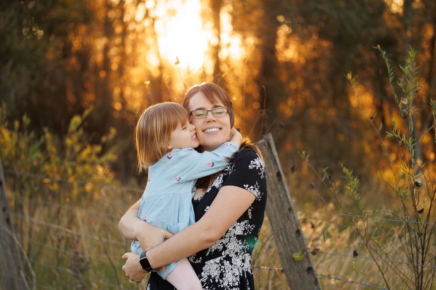 A tender embrace is shared between loved ones in a golden-lit outdoor setting during sunset.
