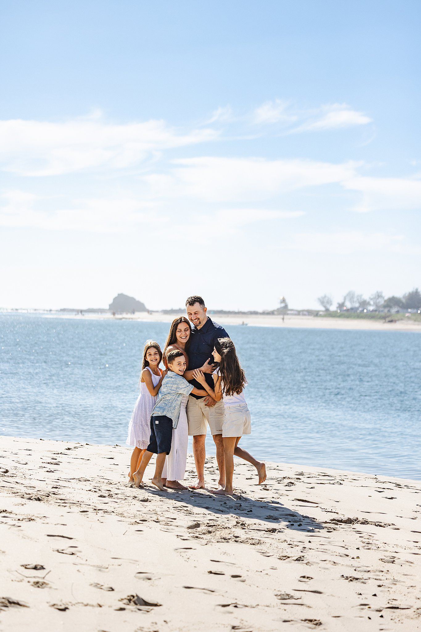 A group enjoys a sunny afternoon together on a peaceful beach with blue water and white sand in the background.