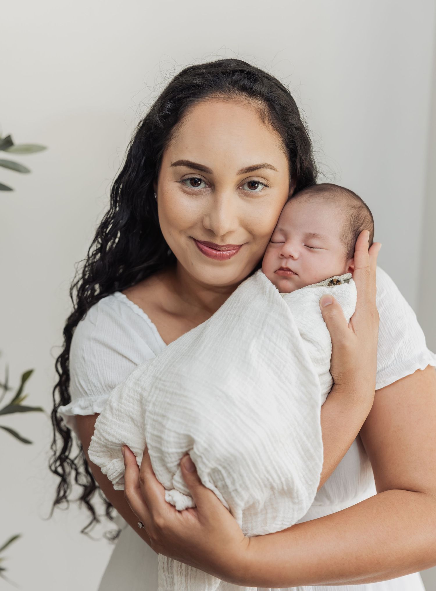 A tender moment captured in a series of intimate white-toned portraits showing parent and baby in matching white outfits.