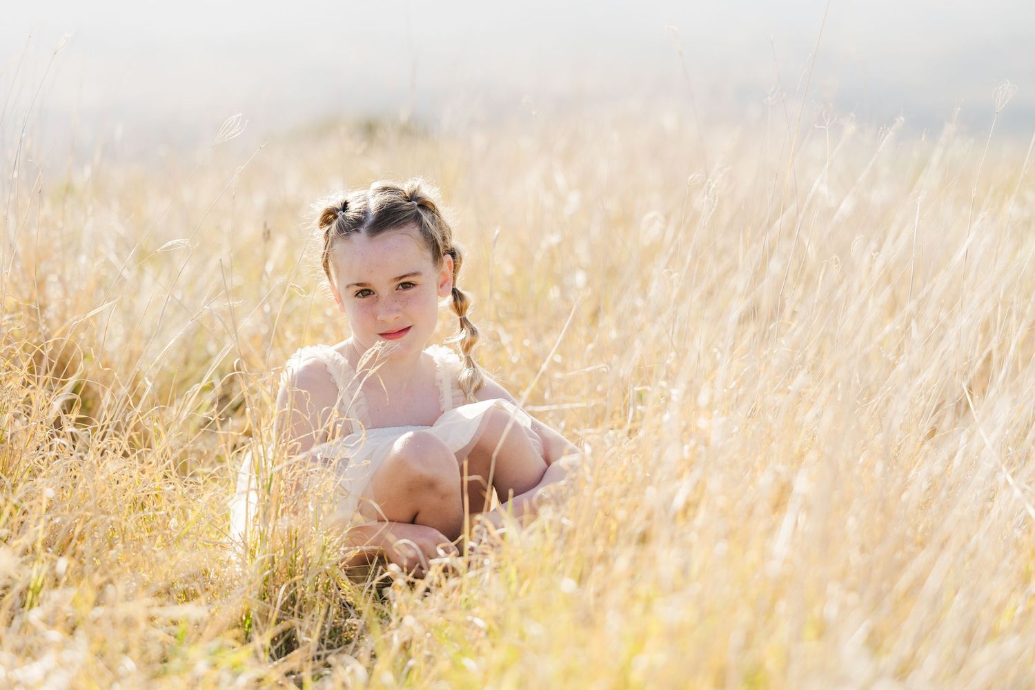 A person sits peacefully in a golden wheat field during sunset creating a dreamy summer scene.