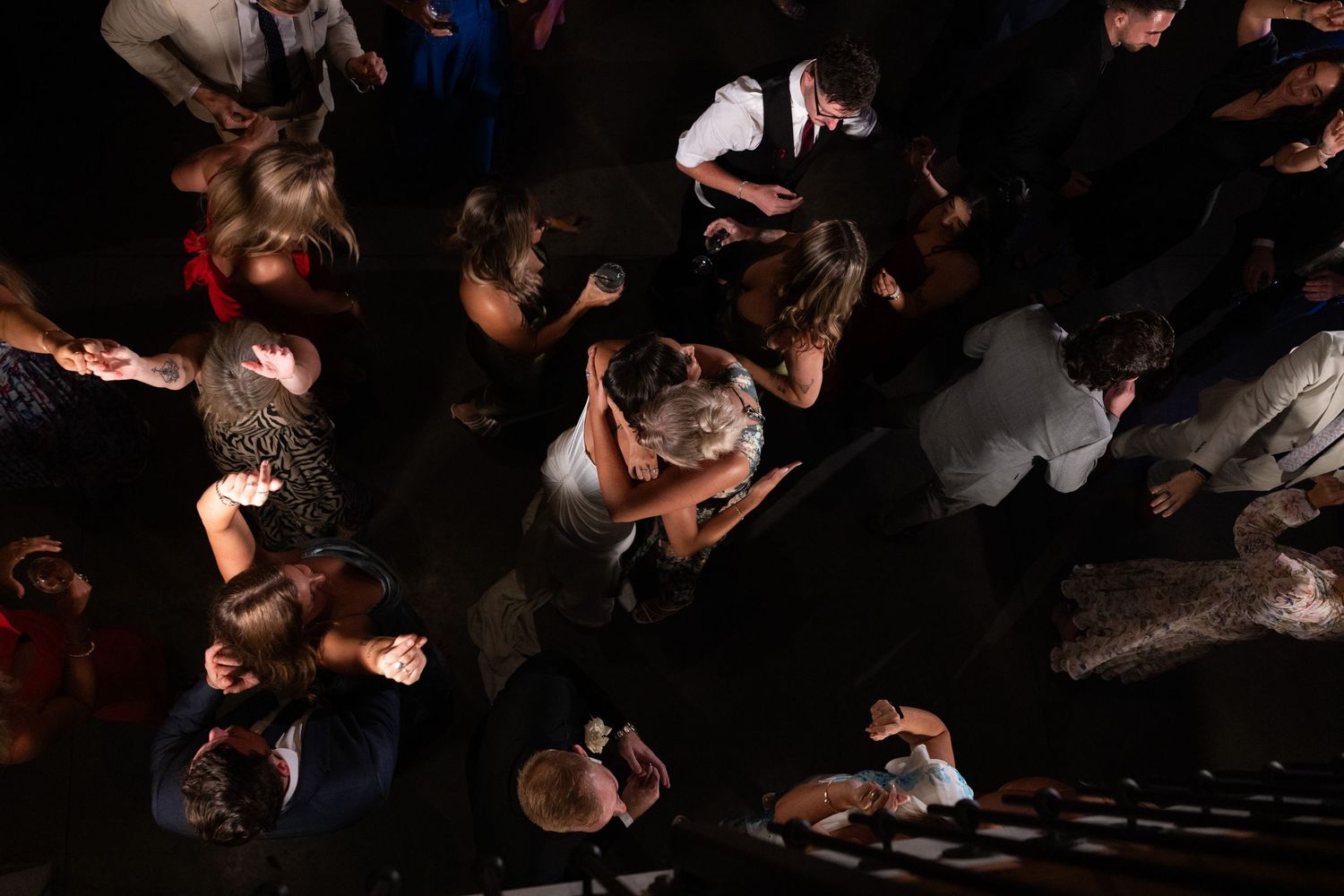 A crowd of people dancing and moving energetically in a dark nightclub or party venue.