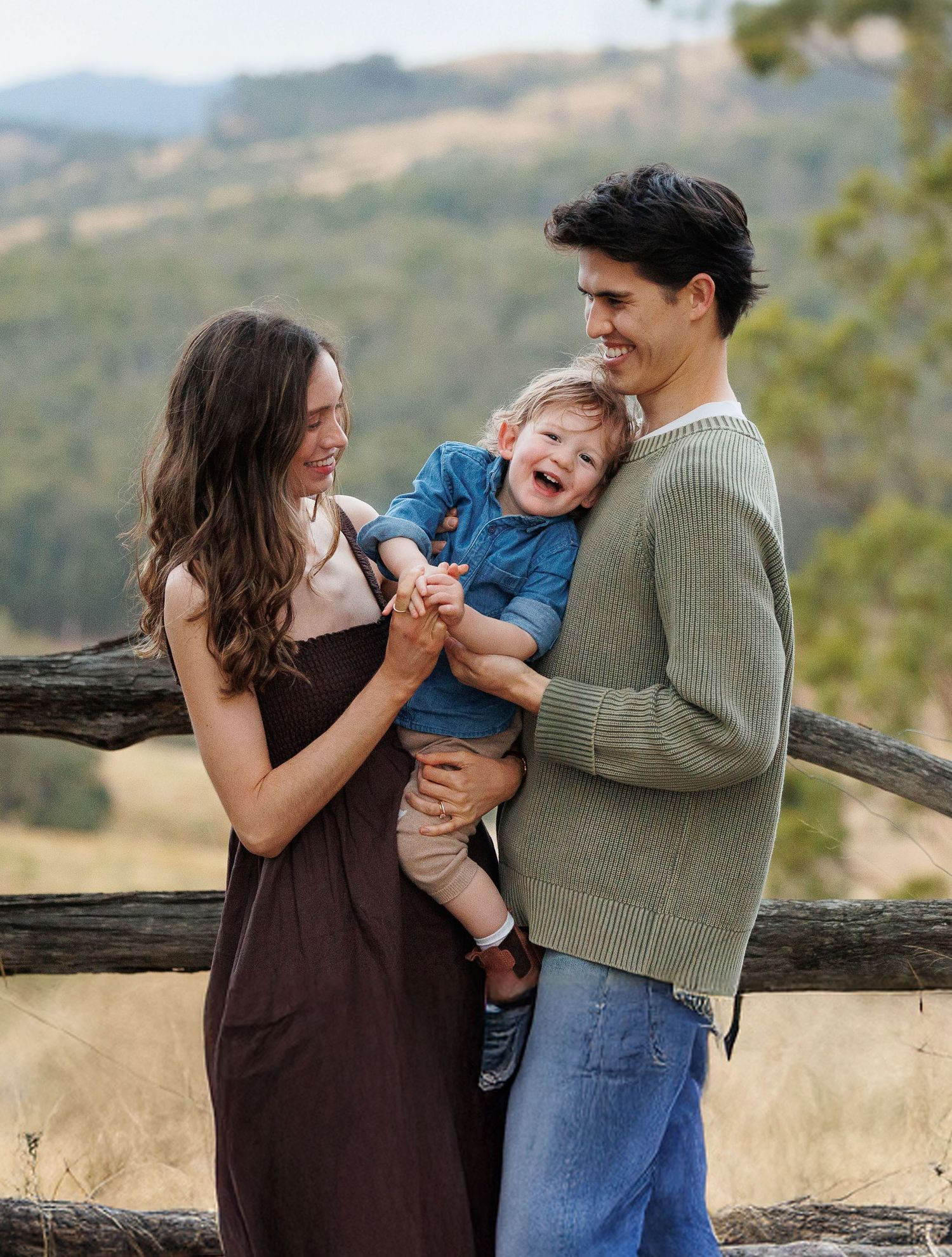 Family shares a candid laughing moment together against a scenic mountain backdrop.