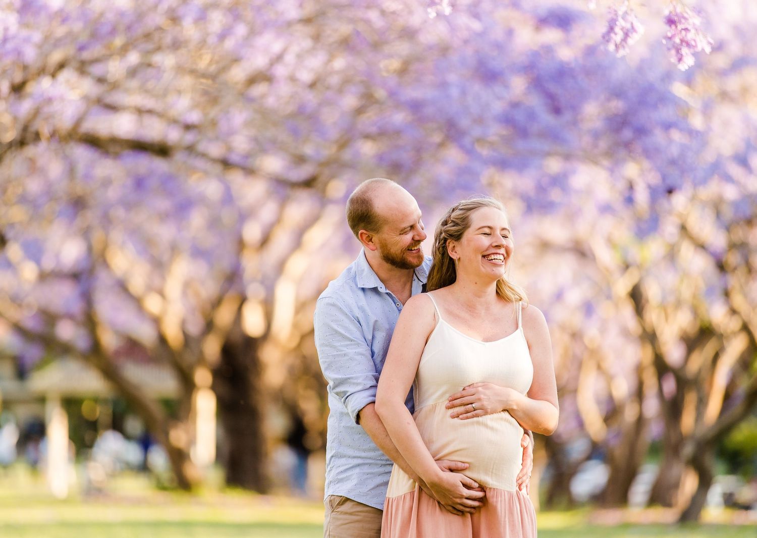 Couple embraces under blooming cherry blossom trees in a romantic spring photoshoot.