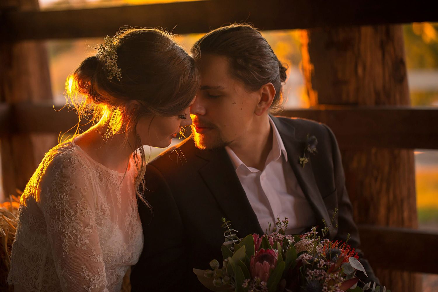 Romantic golden-lit moment between two figures in formal attire during sunset.