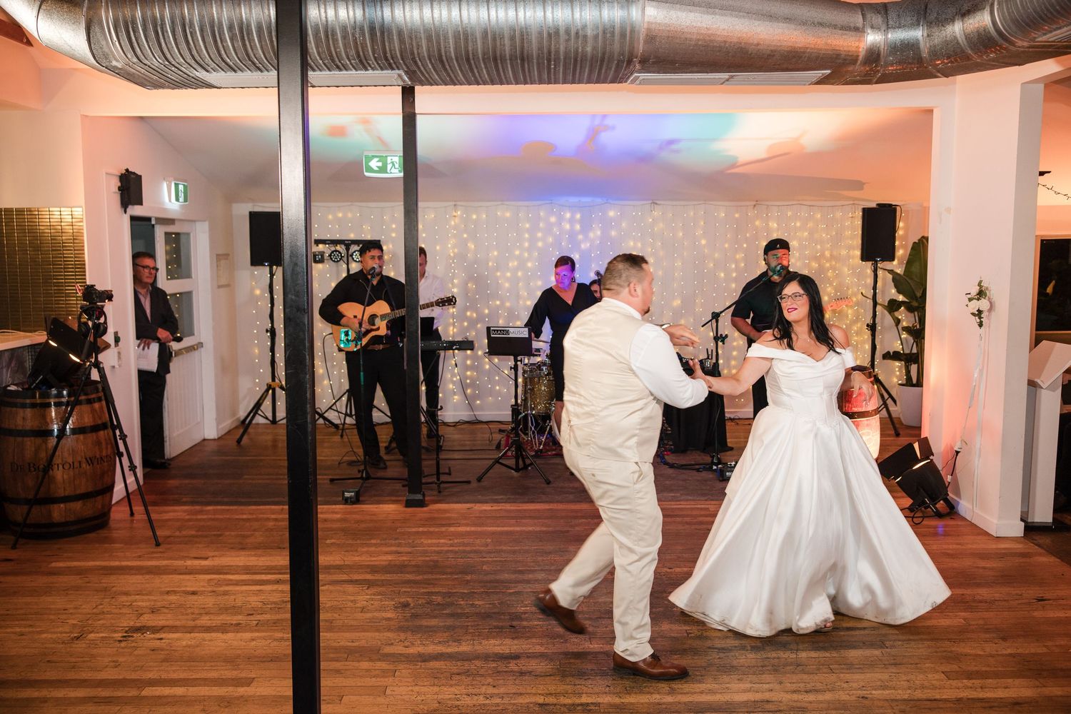 Bride and groom share their first dance at wedding reception with live band performing in background.