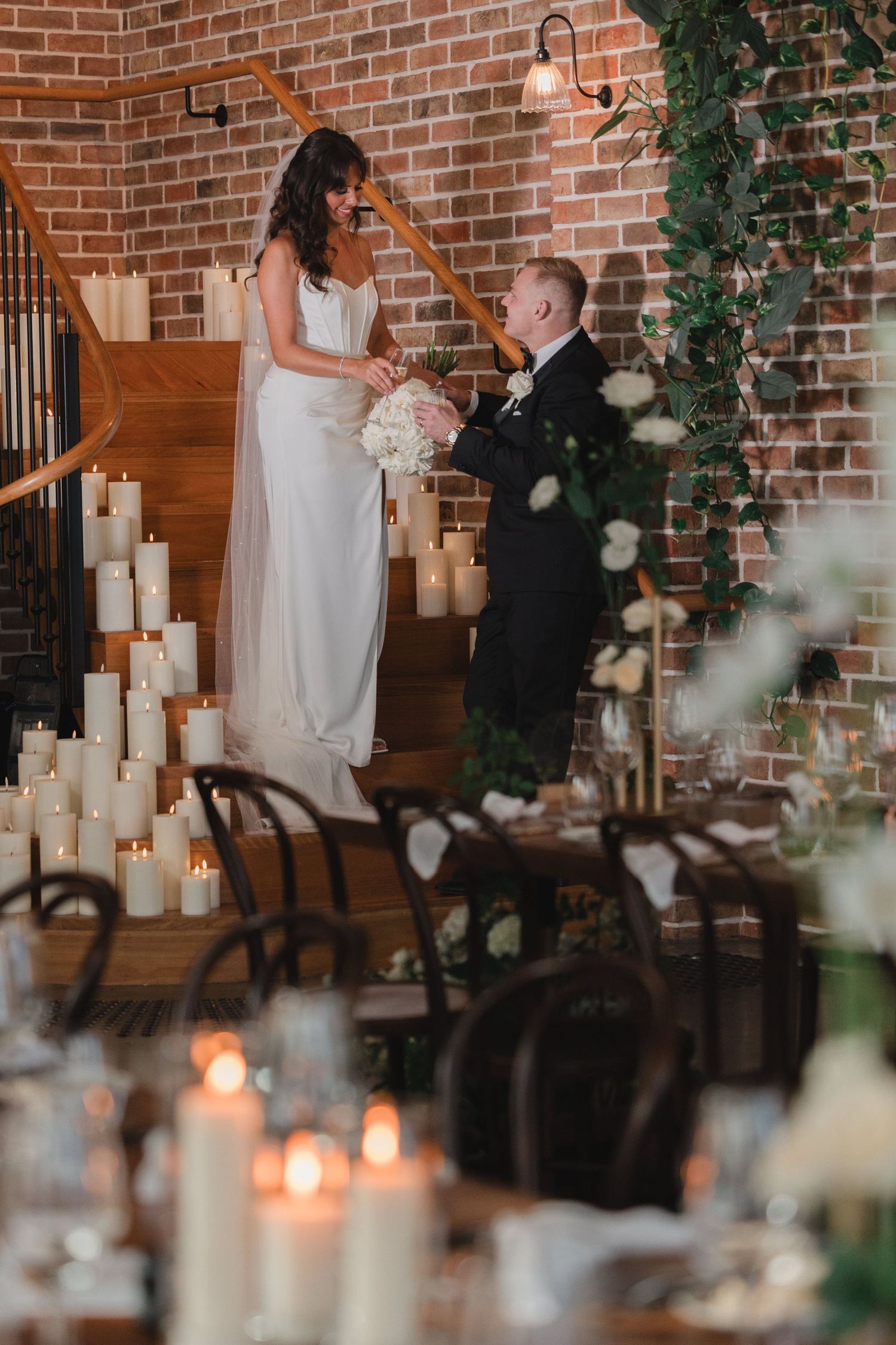 A romantic wedding moment with candles and greenery in an industrial brick venue during an intimate ceremony.