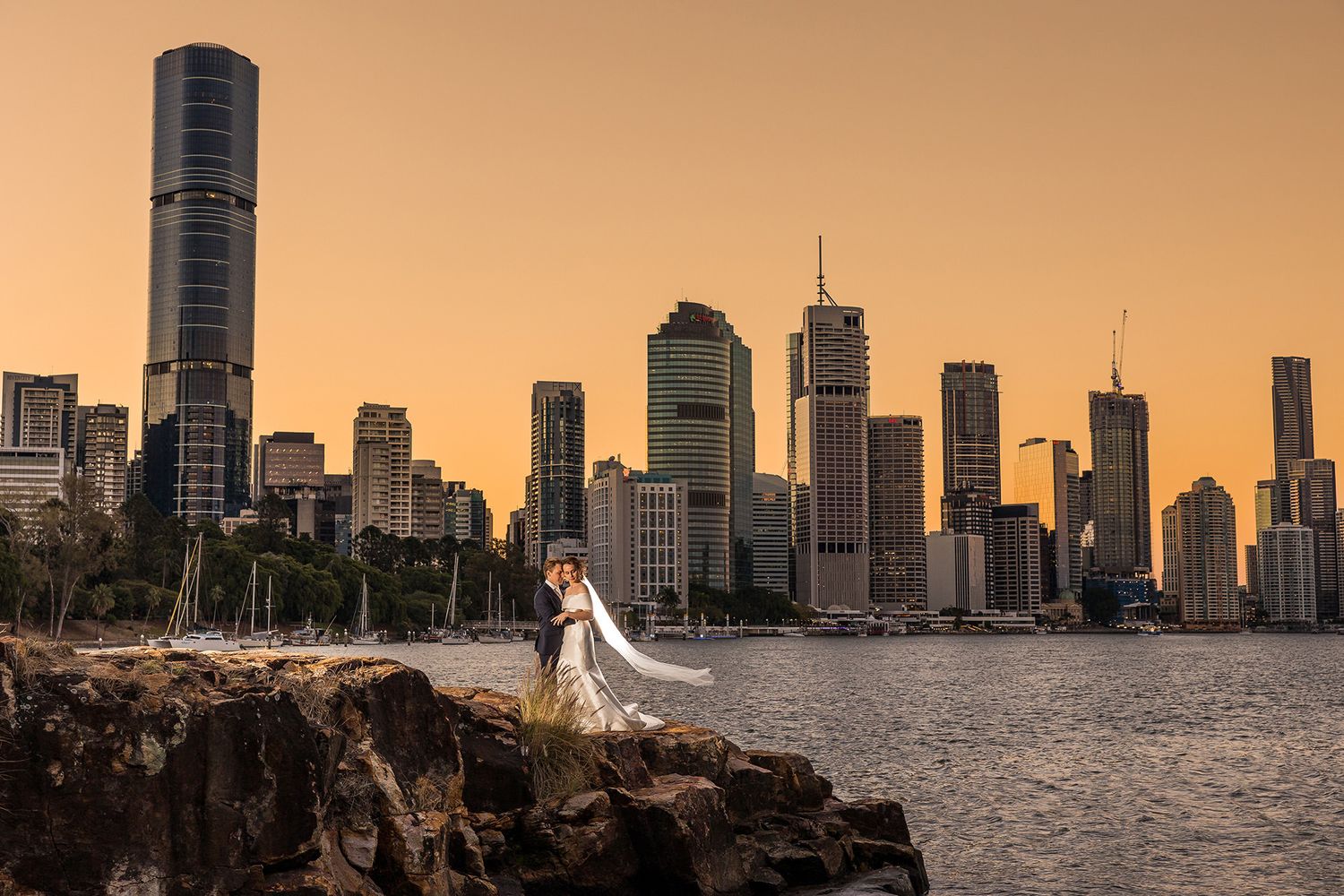 Wedding dress silhouette against Brisbane city skyline at golden hour.
