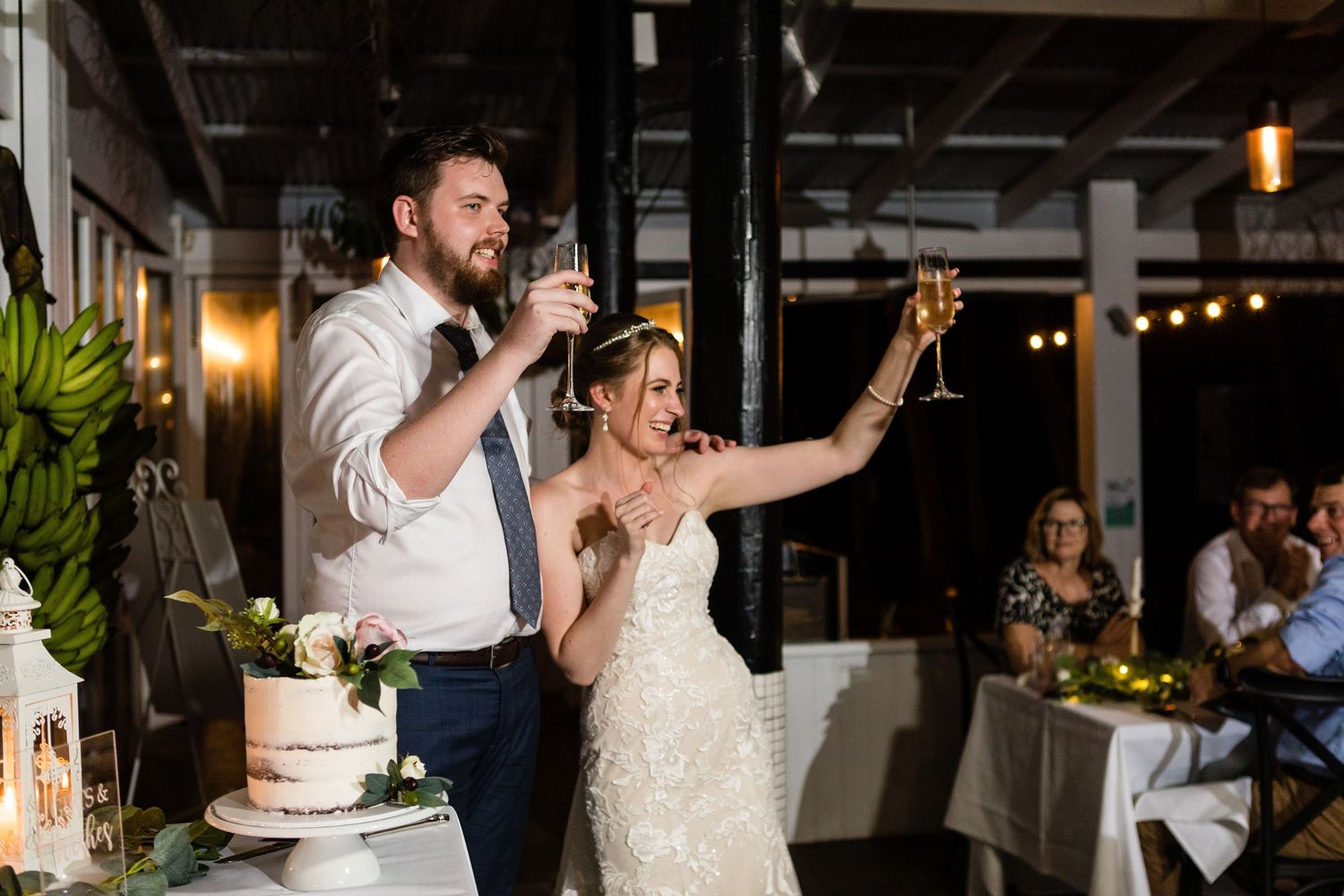 A couple dances together at their wedding reception in an indoor venue with string lights overhead.