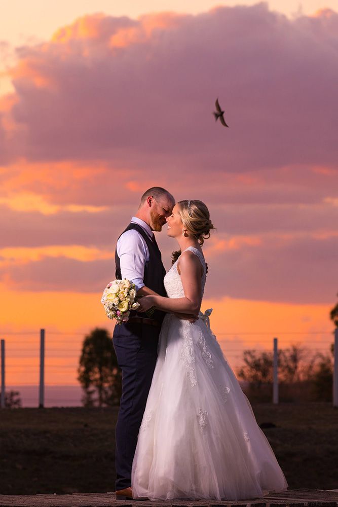 Romantic sunset wedding portrait with a bird soaring overhead.