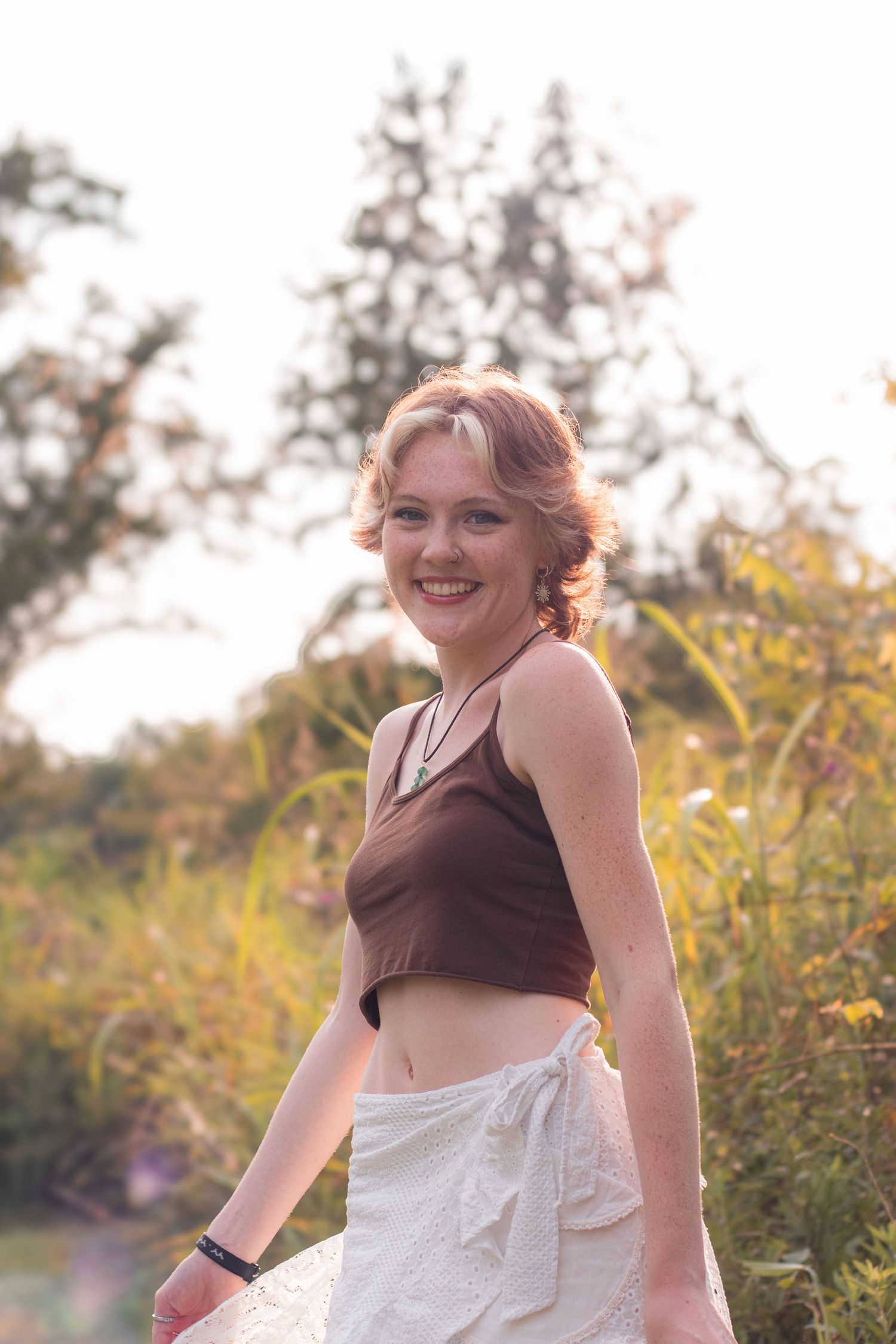 Outdoor senior portrait with blurred natural background and sun flares