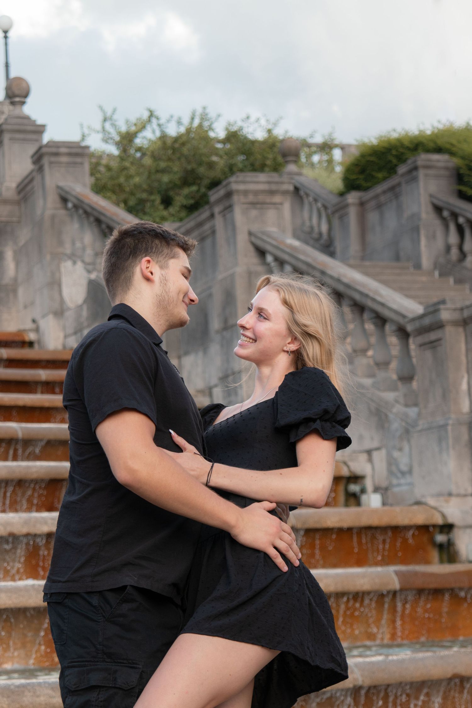 Candid couple photo hugging in front of fountain with soft lighting