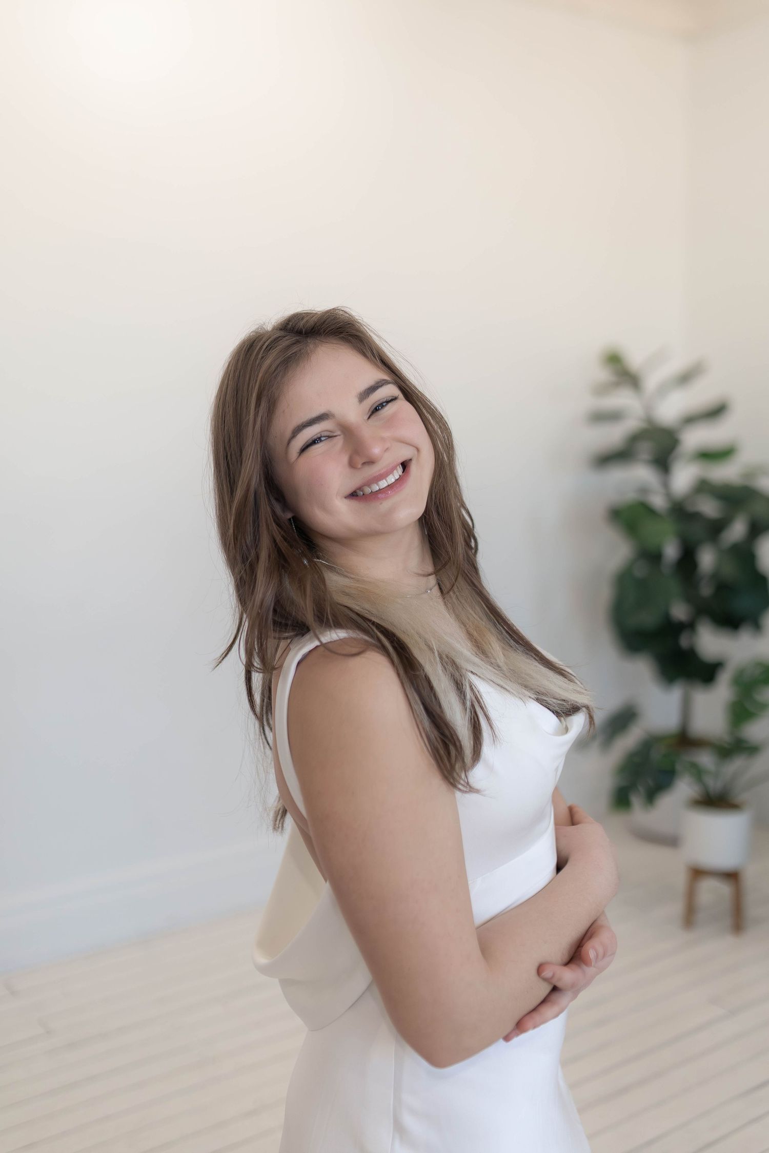 Girl in white dress laughing at the camera in a white studio