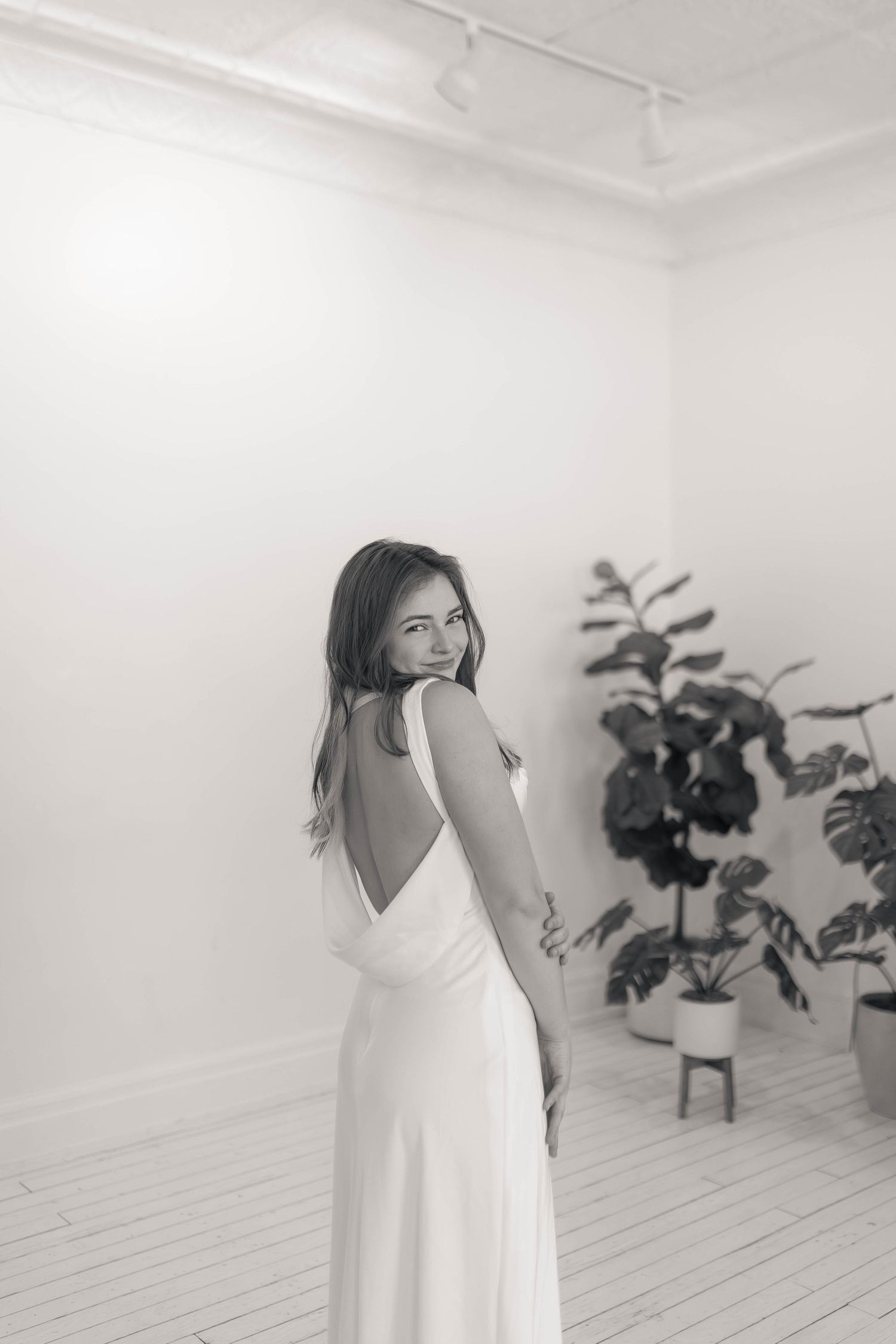 Girl in white dress laughing at the camera in a white studio