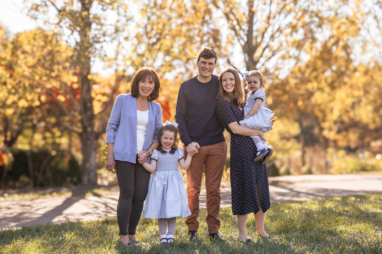 Family portrait in park with parents, grandma, and two kids during fall session
