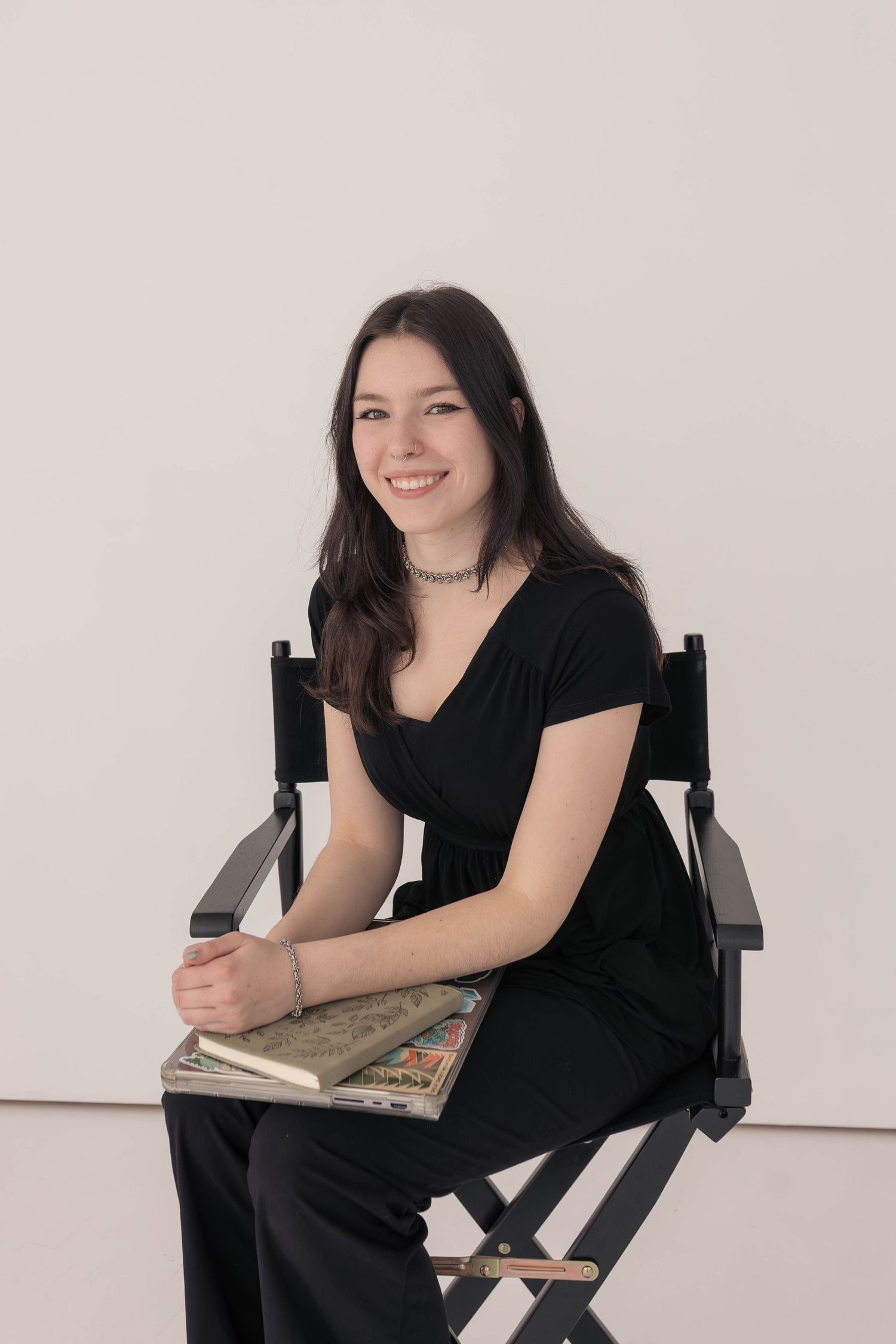 Woman holding computer and sitting in director chair in studio
