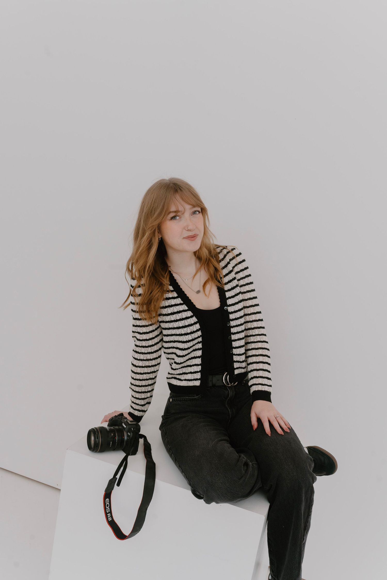 Clean studio branding portrait of photographer with soft lighting and brick backdrop
