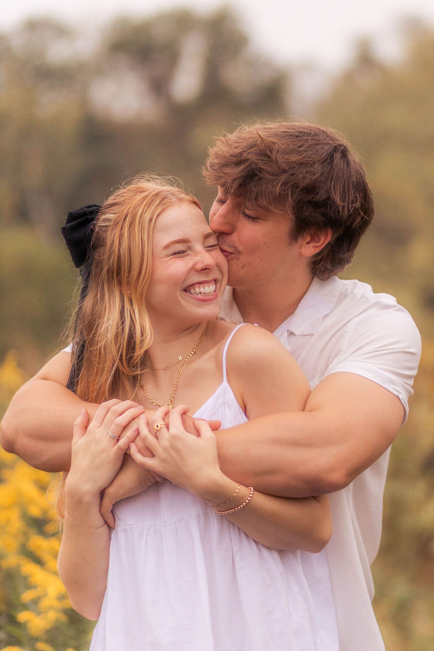Couple smiling and embracing in park during rainy sunset session
