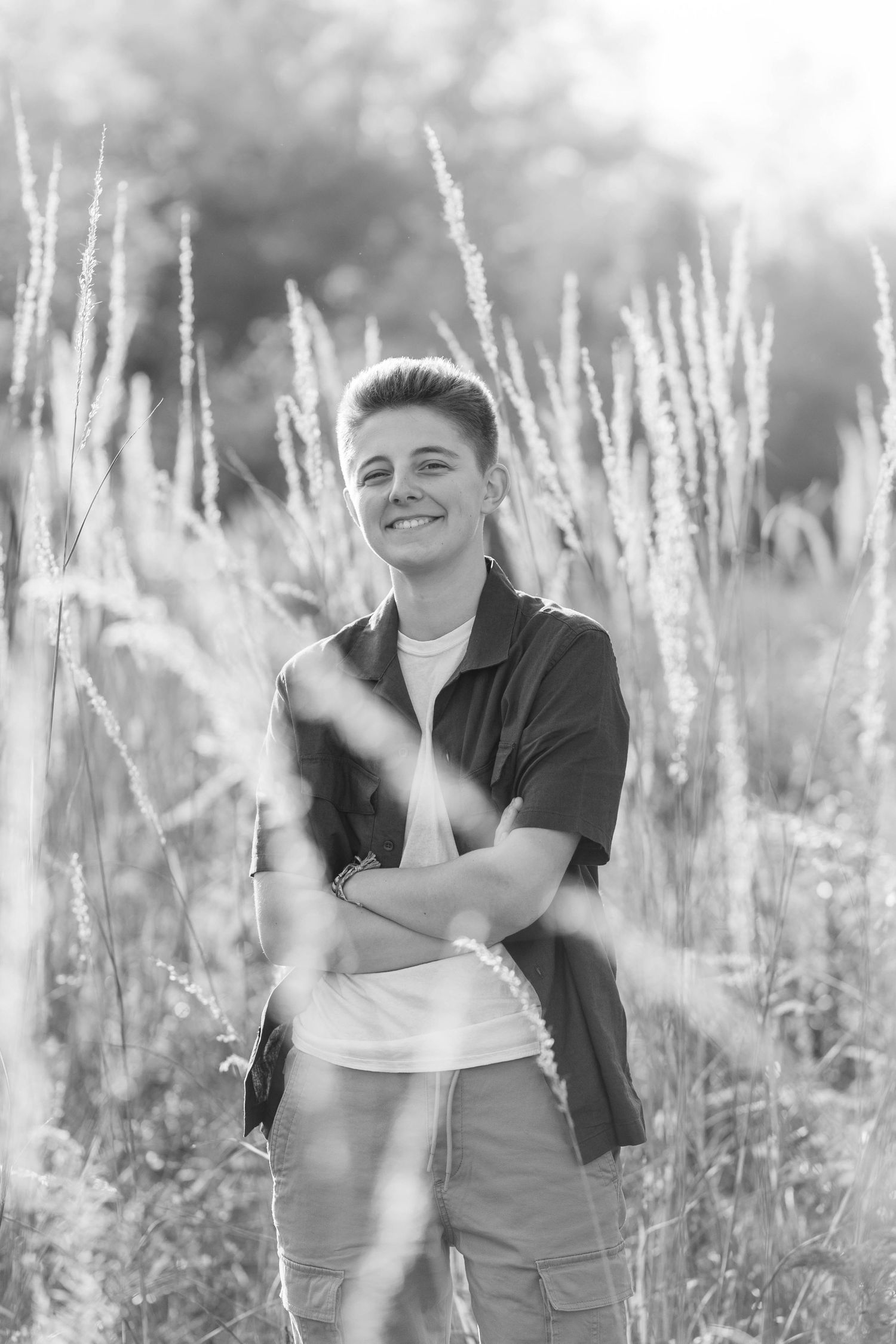 Teen posing in open field for senior pictures in black and white