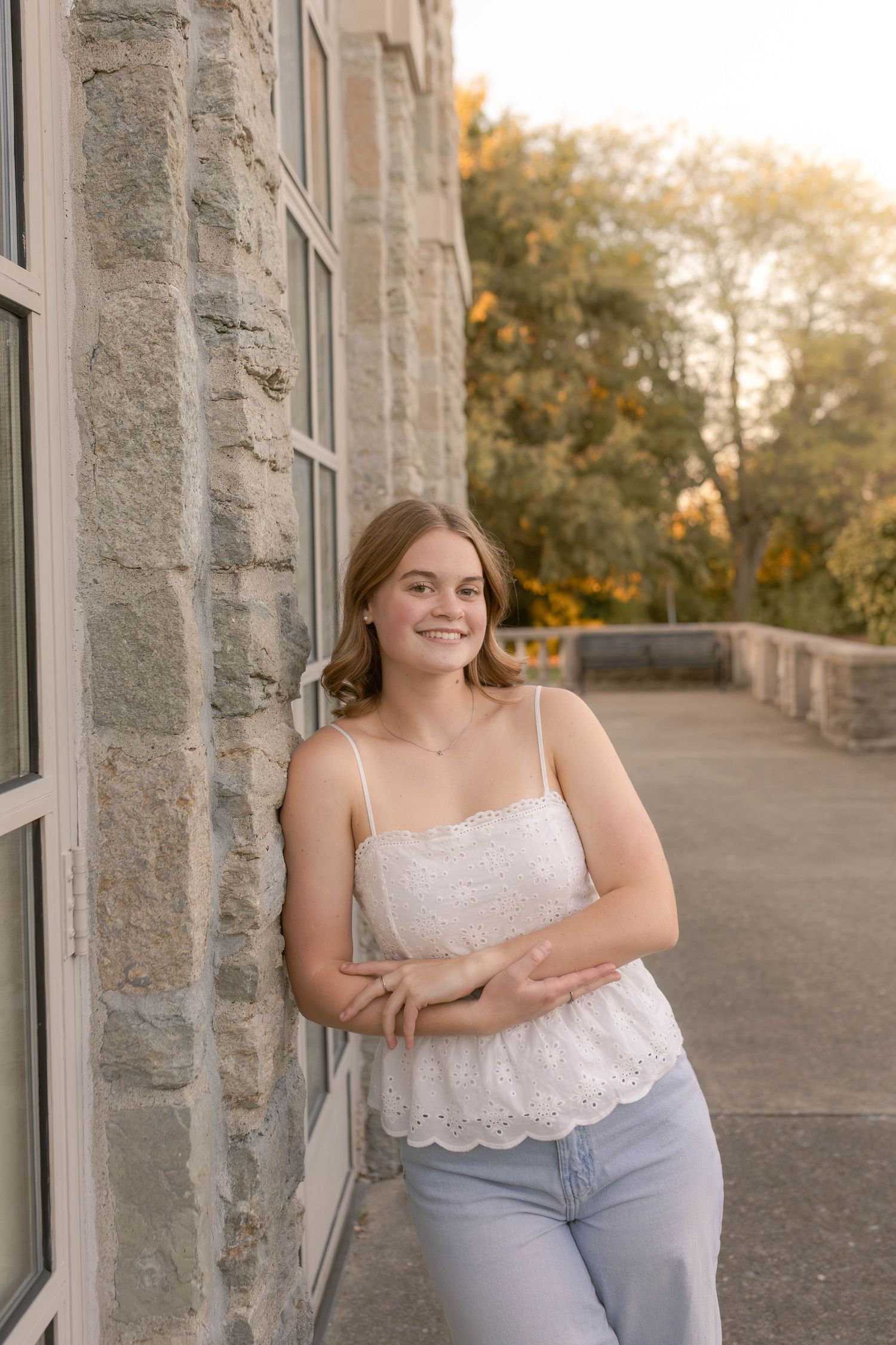 Girl standing and laughing against stone wall